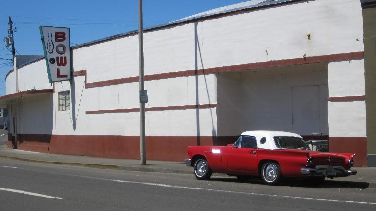 A red and white 1950s Ford Thunderbird in front of the Lower Columbia Bowl in Astoria, Oregon. red 1950s Ford Thunderbird, white top, Lower Columbia Bowl, Astoria, Oregon