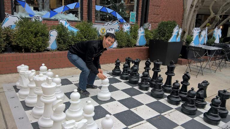 Felix Wong moving a chess piece on the giant chess board outside World Chess Hall of Fame. Felix Wong, giant chess board outside World Chess Hall of Fame
