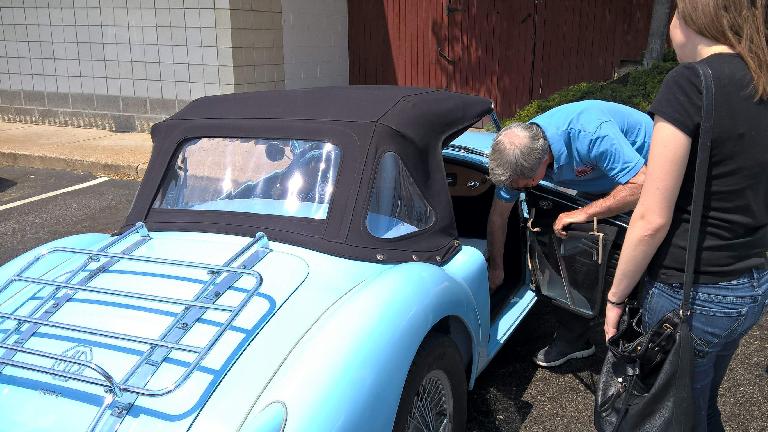 Mike Jacobsen shows Maureen the side curtains on his light blue MGA roadster. Mike Jacobsen shows Maureen the side curtains on his light blue MGA roadster.