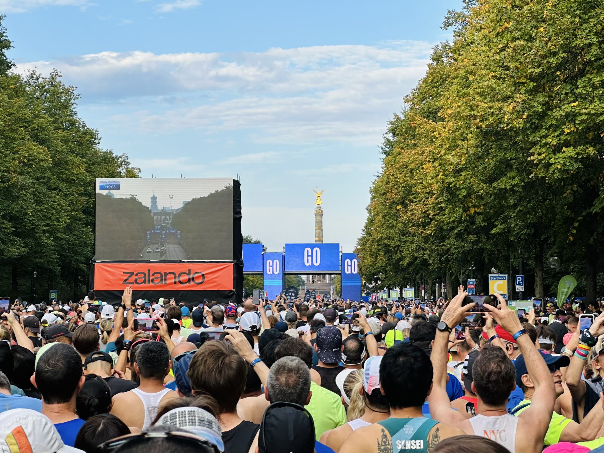 Runners waiting in the A, B, C, and D waves with large digital screens reading "Go" on each one