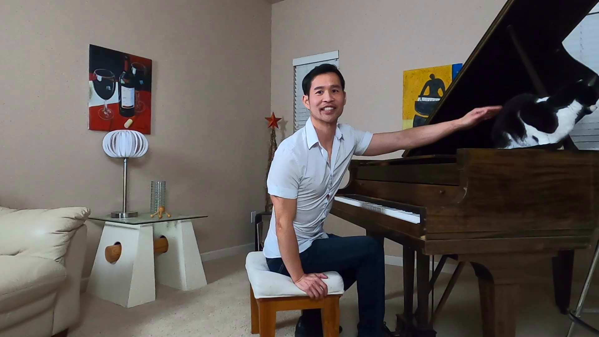 Felix Wong, white shirt, petting black & white cat, piano in living room