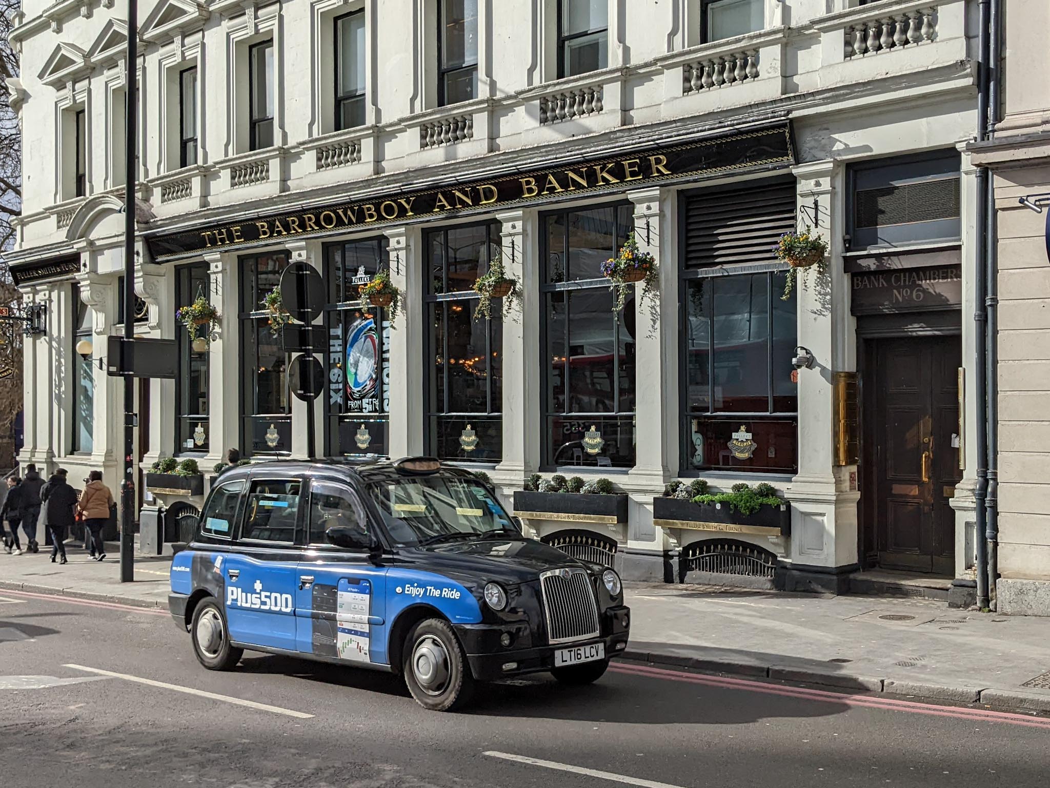 A blue/black London Taxi sponsored by Plus500.