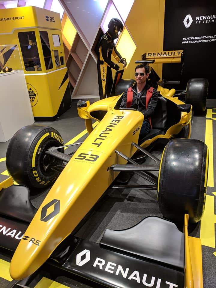 Felix Wong inside a yellow Renault race car at the Renault showroom on the Champs-Élysées.