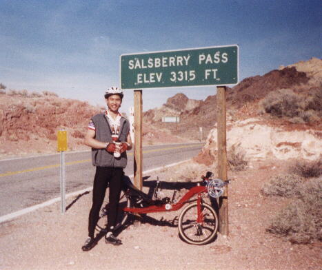 Felix Wong and his red Reynolds Wishbone recumbent, Salsberry Pass sign, elevation 3315 ft., 2000 Death Valley Double Century