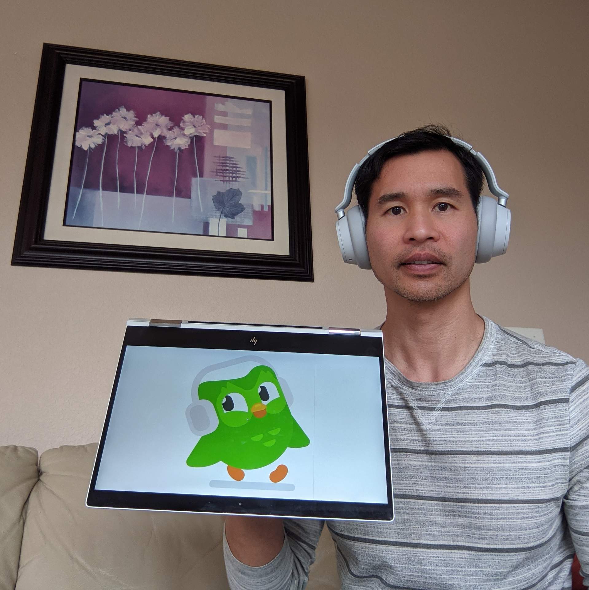 Duo the green Duolingo owl and Felix Wong wearing similar Microsoft Surface Headphones