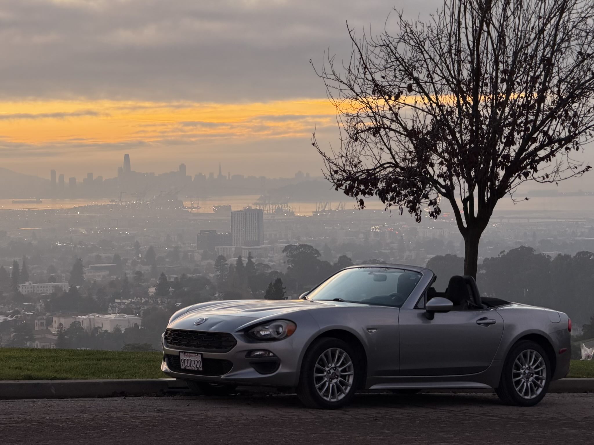 The Aluminum Metallic 2017 FIAT 124 Spider Turo rental with the San Francisco Bay and city in the background.