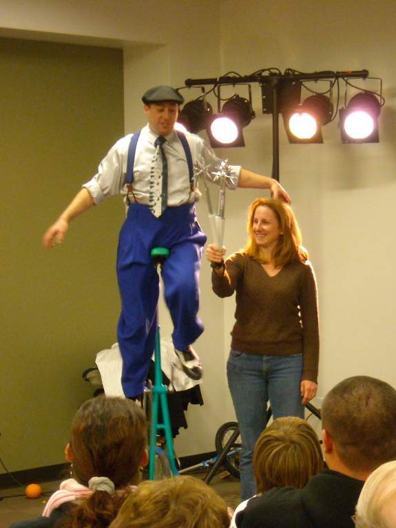 Reid Belstock about to juggle some sharp metal objects while riding a unicycle.