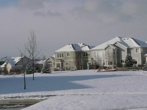 a couple inches of snow on field in with three large homes