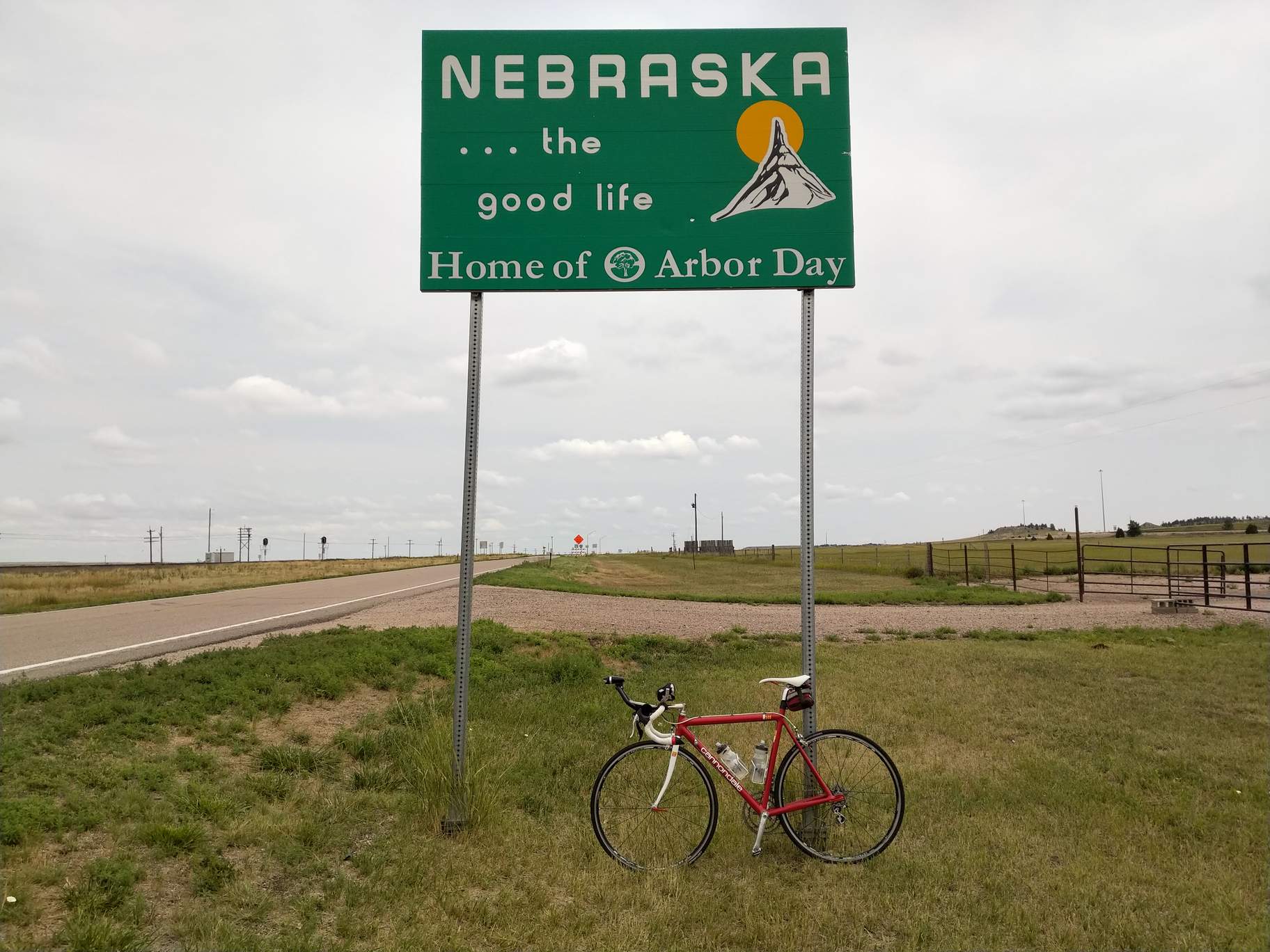 My red 1992 Cannondale 3.0 with the Nebraska state border sign. The irony of the slogan "Home of Arbor Day" was not lost on me in this particular area where there was not a single tree nor bush.