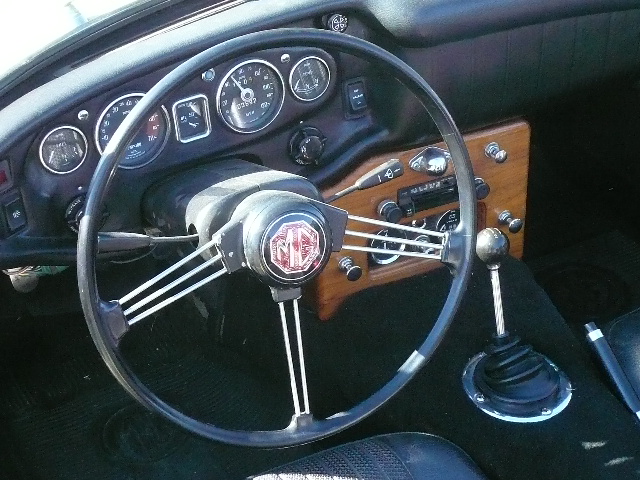 interior of 1969 MGB with custom wooden dash, banjo steering wheel, gauges and stick shift