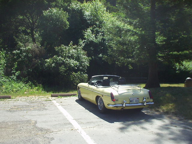 yellow MGB roadster with top down and tonneau cover on in parking lot