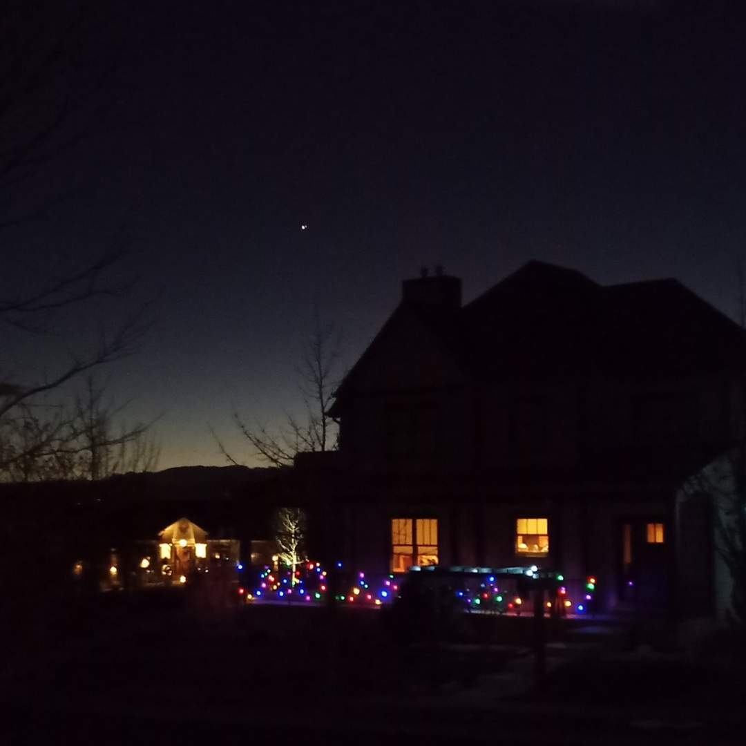 Great Conjunction of Jupiter and Saturn over two-story house decorated with Christmas lights