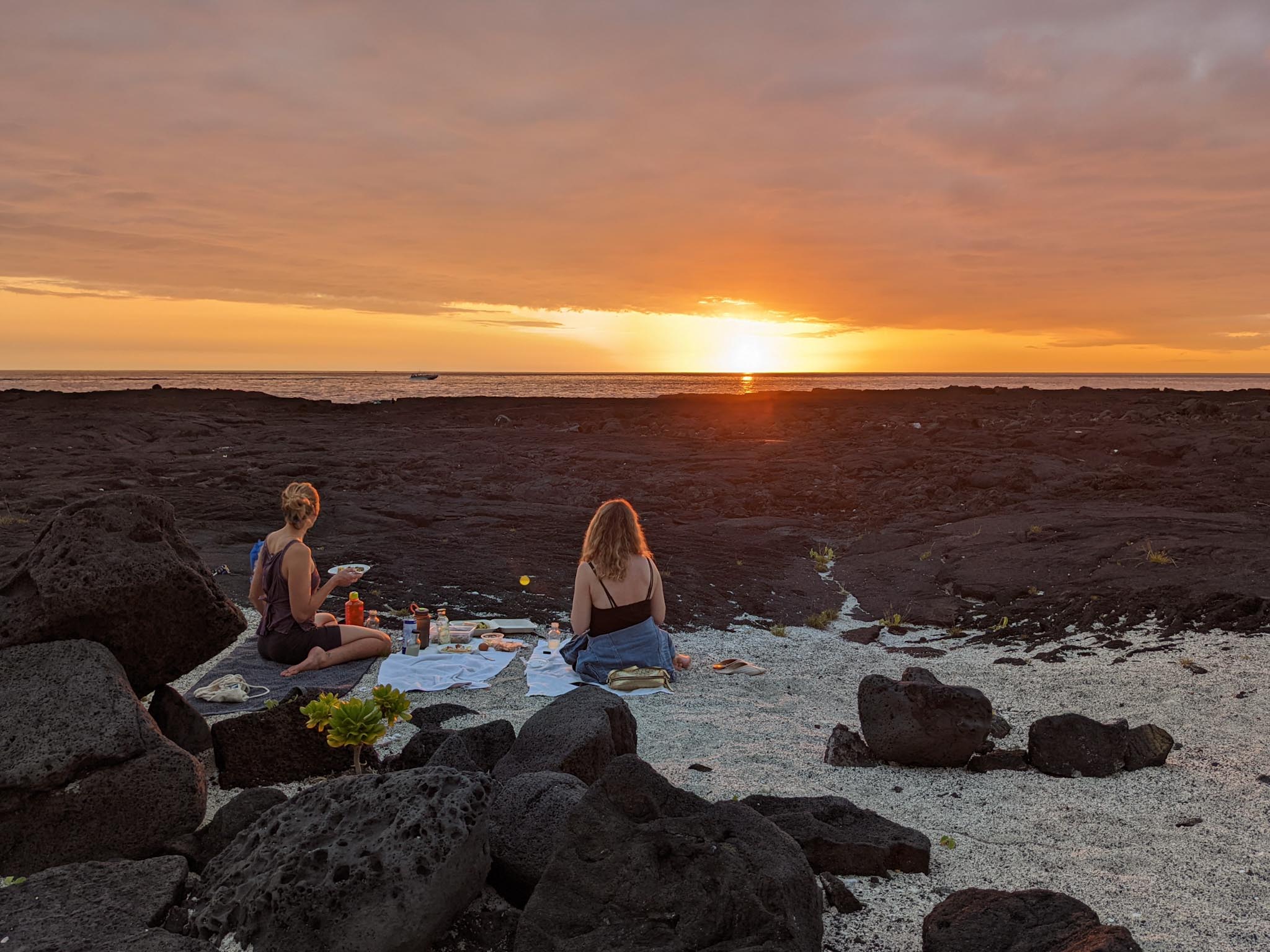Erin and Andrea having a picnic while watching a sunset at Kohanaiki Beach Park.