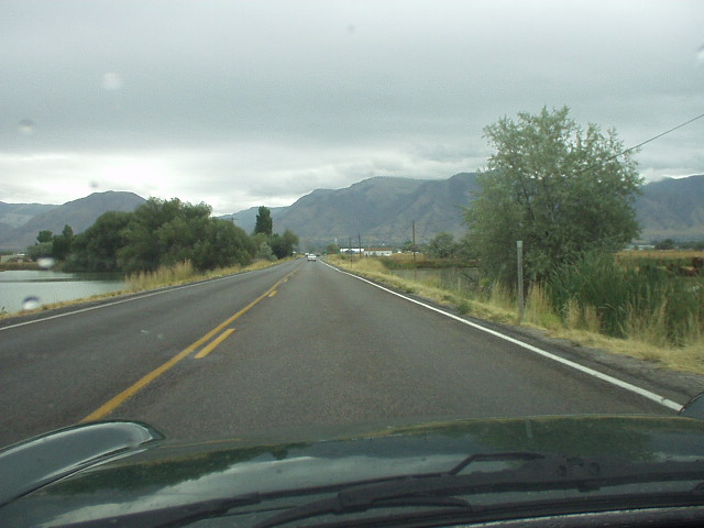 view from driver's seat while driving down road towards mountains near Logan, Utah.