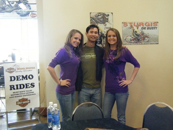 Natalie Campbell, Felix Wong, Jennifer Campbell in between a Demo Rides sign and Sturgis poster