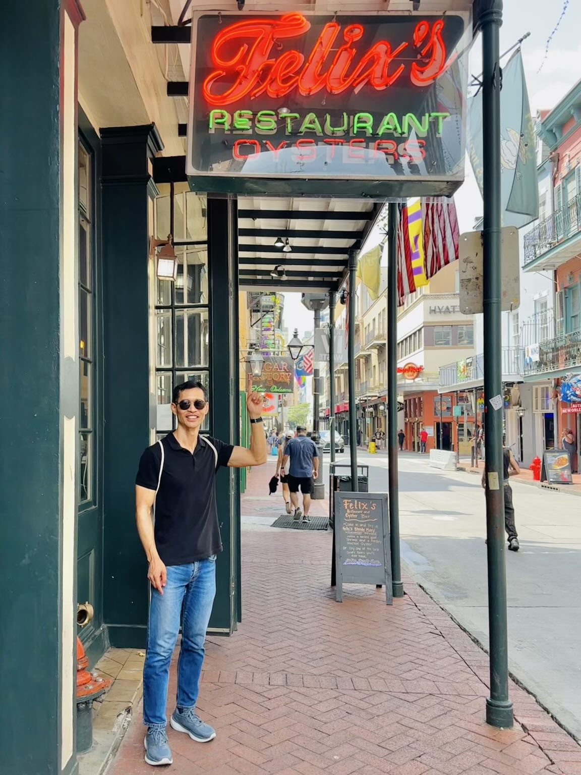 Felix pointing to upwards at a sign saying "Felix's Restaurant Oysters" in the French Quarter of New Orleans.