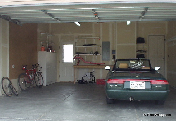 garage with green 1991 Alfa Romeo Spider convertible with top down and ladder in the passenger side of the car.