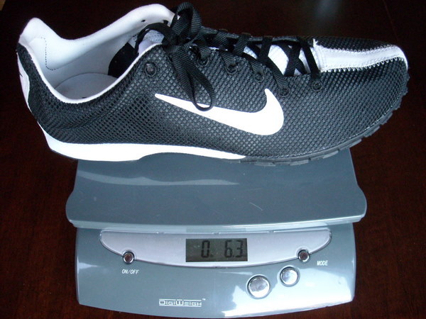 a Nike Zoom Waffle Racer Vii shoe on a postal scale weighing 6.3 ounces.