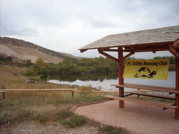 pavilion with yellow Ft. Collins Running Club banner in front of lake 