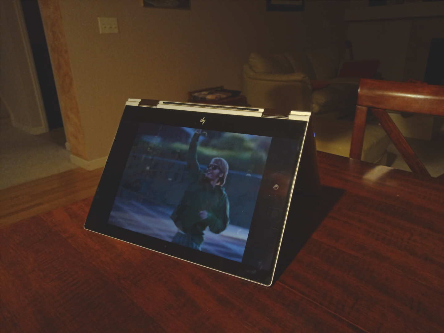 picture of Steve Prefontaine in green shirt with arm raised on screen of an HP Spectre x360 convertible laptop on a wooden table
