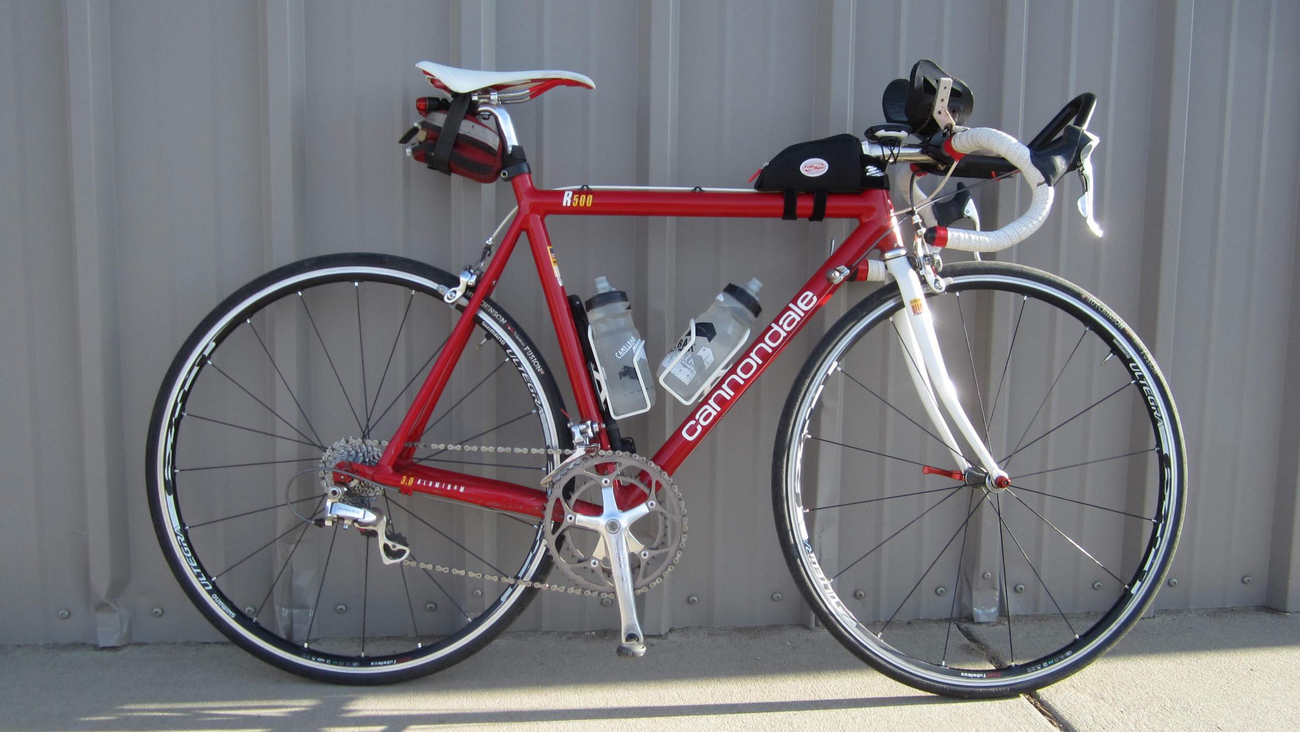 Red Cannondale 3.0 road bike, white saddle and fork, aerobars