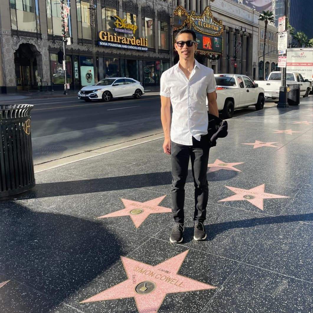 Felix Wong behind the Simon Cowell star on the Walk of Fame with Ghiradelli in the background.