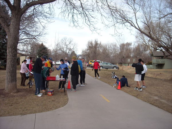 runners standing around next to small table and orange cones on Spring Creek Trail