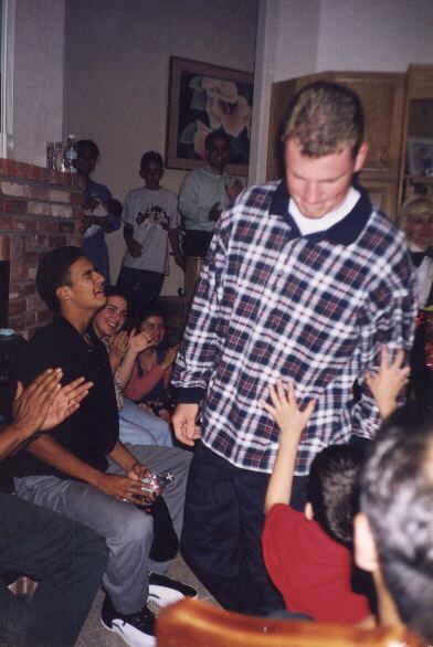 Stephen Cook in a plaid shirt with lots of friends at a party.