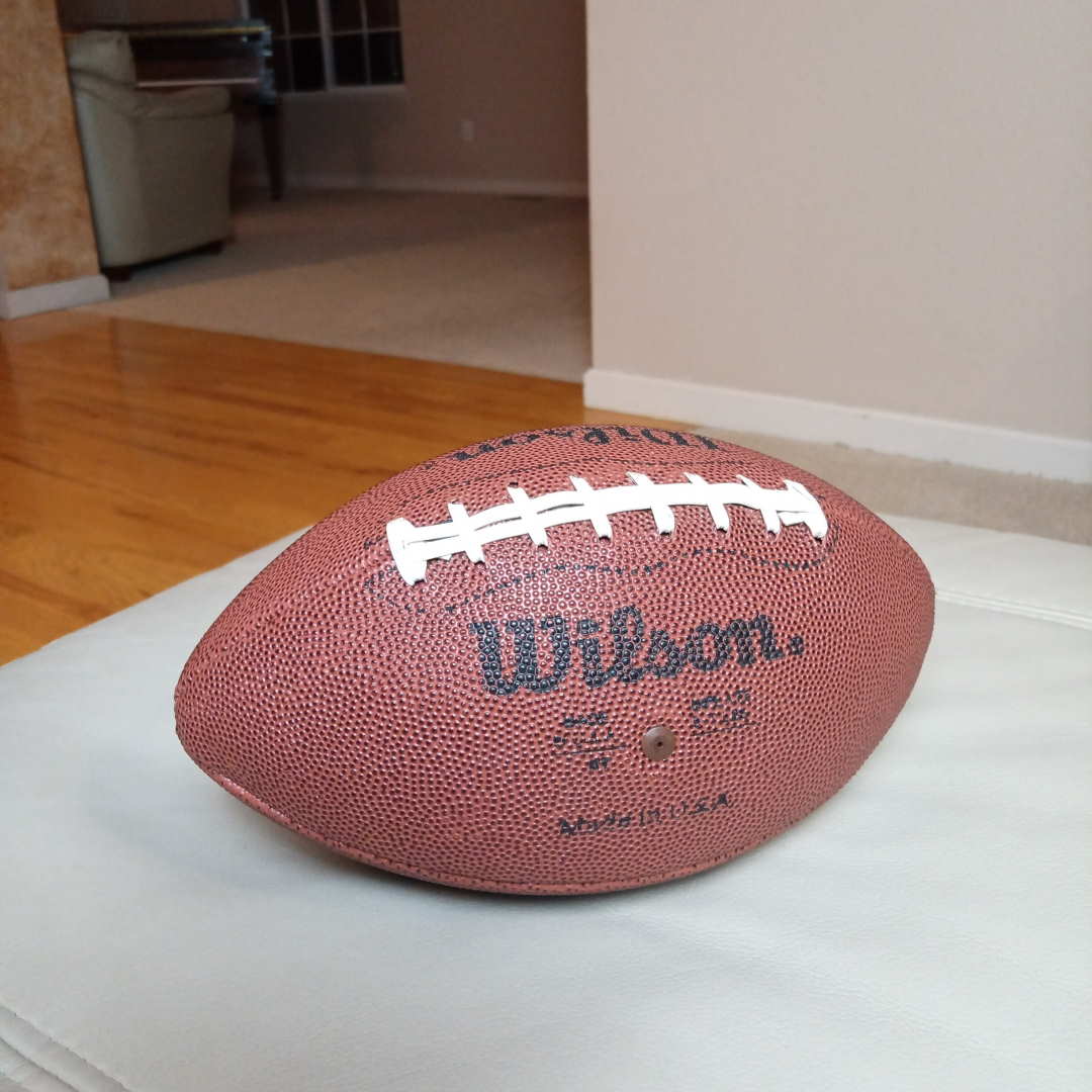 A Wilson football on an ottoman.