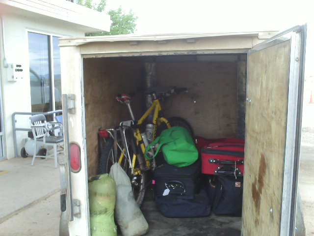wooden trailer with rear doors open, yellow Cannondale mountain bike inside with luggage and bags