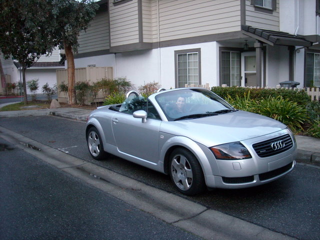 silver 2001 Audi TT Roadster Quattro with top down and woman in the driver's seat at a condominium complex