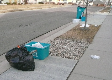 black garbage bag with metal exhaust pipe sticking out, turquoise Gallegos recycle bin on sidewalk
