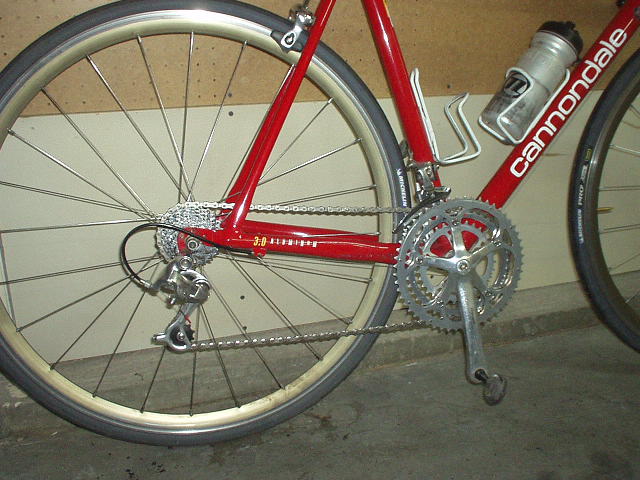 lower rear part of a red 1992 Cannondale R500 3.0 road bike with very shiny chain and triple chainring