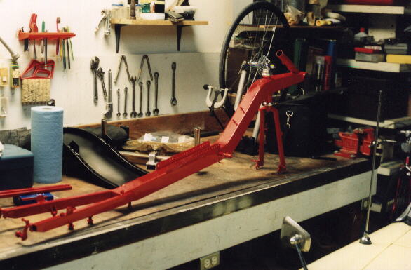 Reynolds Wishbone recumbent frame on a workbench painted Porsche Guards Red.
