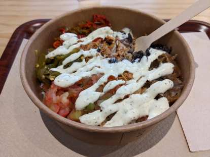A bowl of shredded chicken, beans, tomatoes, jalapeños, and onions covered with a white sauce from the Gazteca restaurant in A Coruña.