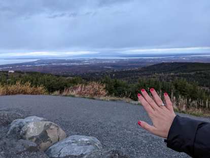 The diamond ring on Andrea's right hand, with a distant view of Anchorage and the sea in the background.