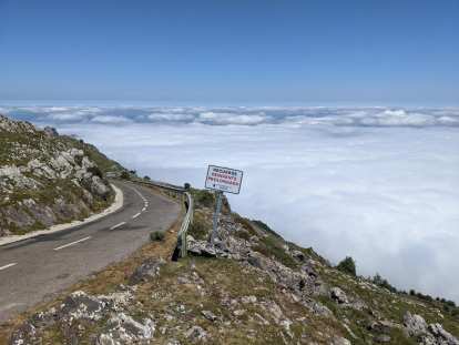 road above the clouds and a sign that reads "recuerde pendiente prolongada" not far from the top of Angliru.