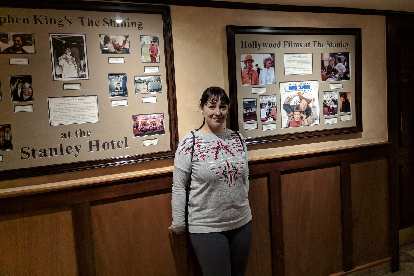 Vicky in front of photos of Hollywood movies filmed at the Stanley Hotel.