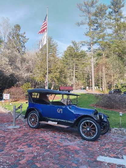 A blue antique car and a U.S. flagpole in front of the Grove Park Inn in Asheville, North Carolina.