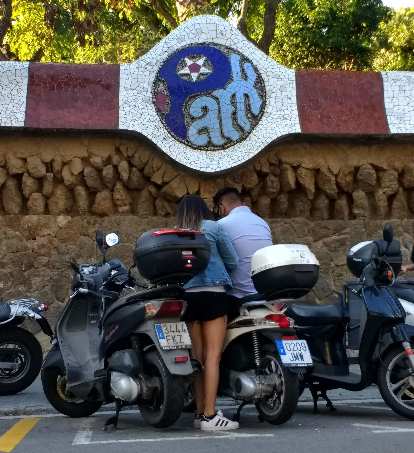 A woman with a man on a motorbike underneat the Park Güell sign. (20 Sep 2017) A woman with a man on a motorbike underneat the Park Güell sign.