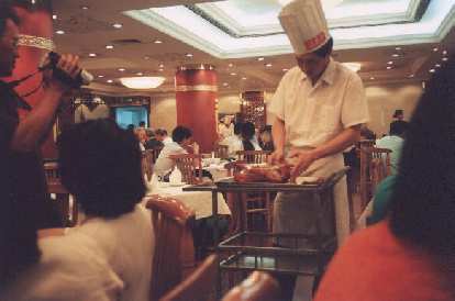 A chef preparing Peking duck for dinner at "Beijing's best Peking duck restaurant" with our tour group's "Captain Video" filming at the left.