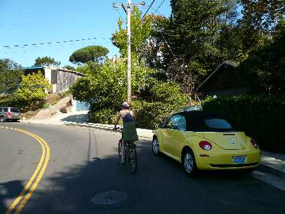 Sarah going up Spruce St., past a yellow Beetle.