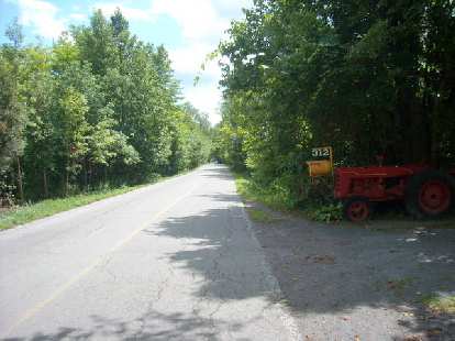 [Mile 337] A red tractor by a yellow mailbox in the quebecois countryside.