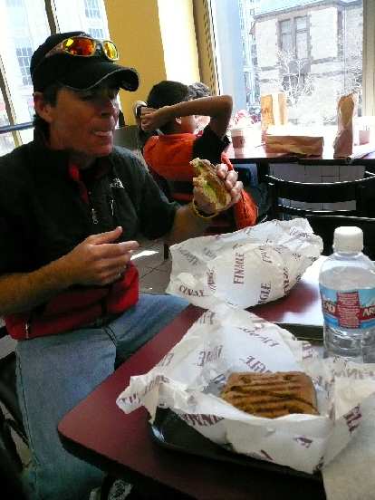 Eddie eating a sandwich at Finnagle A Bagel.
