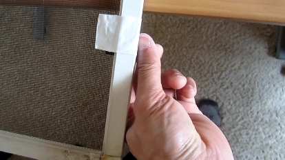 Using duct tape to replace a broken window screen pull tab.