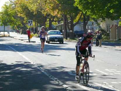 The first runner was so far ahead that he cruised into the finish behind this cyclist.