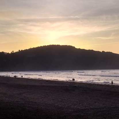 Surfers along the beach of La Arena, Spain.
