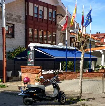 A scooter outside a hotel with flags in Galizano, Spain.