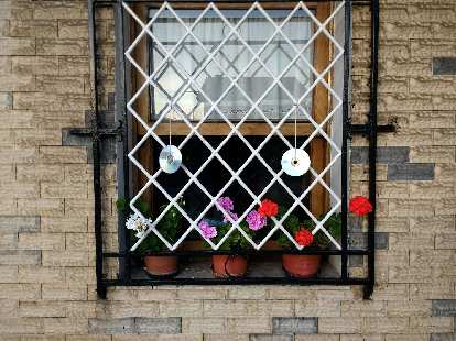 CDs upcycled as art and flowers in a window in a town west of Santander, Spain.