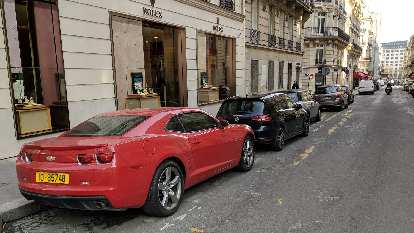 A red, fifth-generation Chevrolet Camaro on a street in Paris.